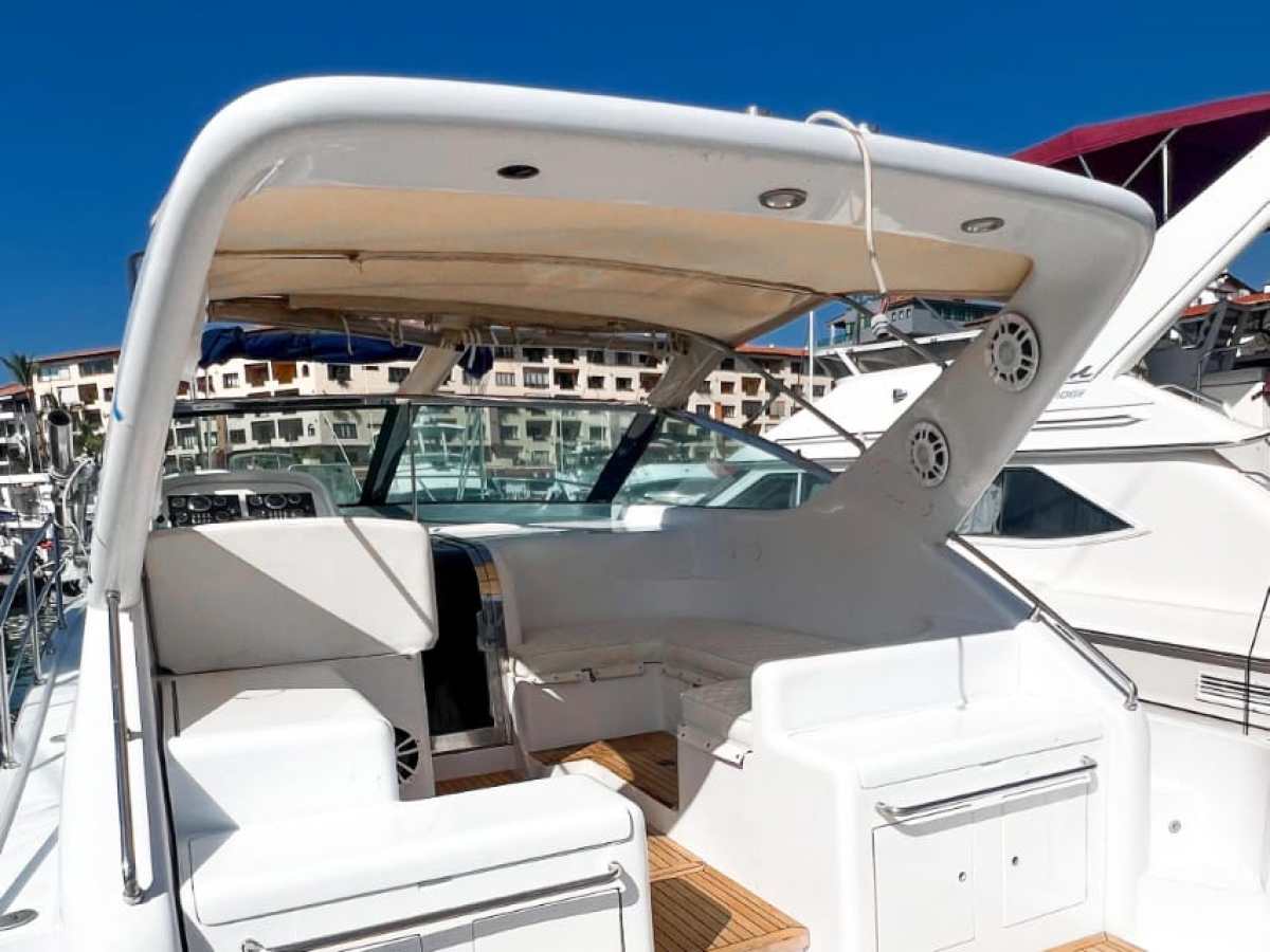 View of a boat's deck with white seating and wooden flooring under a clear blue sky.