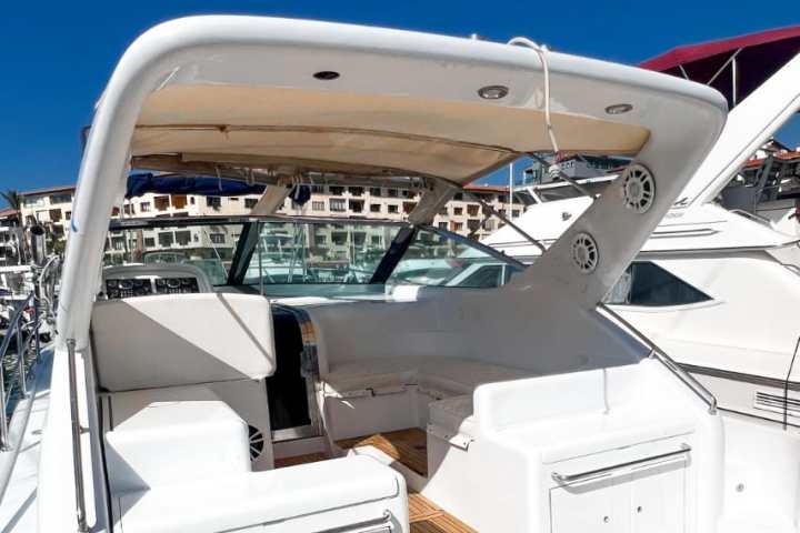 View of a boat's deck with white seating and wooden flooring under a clear blue sky.