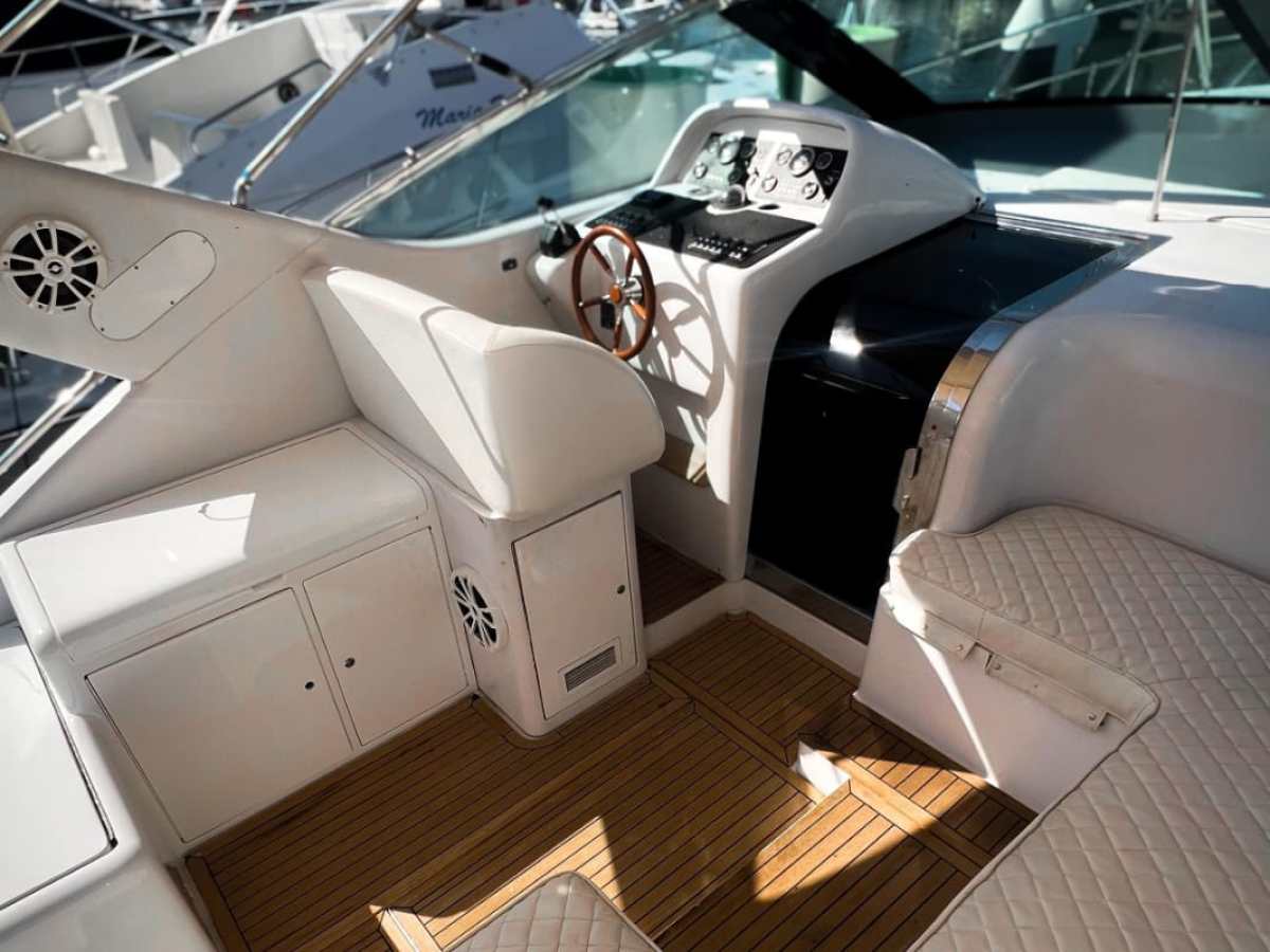 Interior of a yacht with seating and a steering wheel.