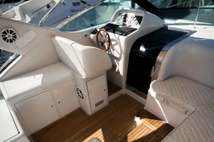 Interior of a yacht with seating and a steering wheel.