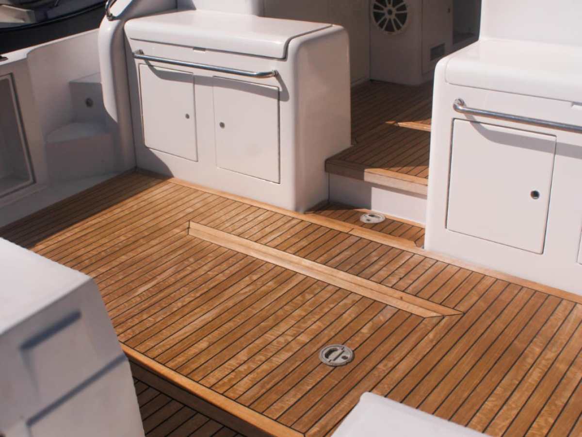 Interior of a boat showing wooden deck and white seating.
