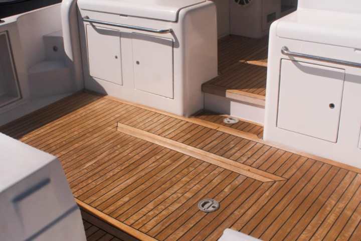Interior of a boat showing wooden deck and white seating.