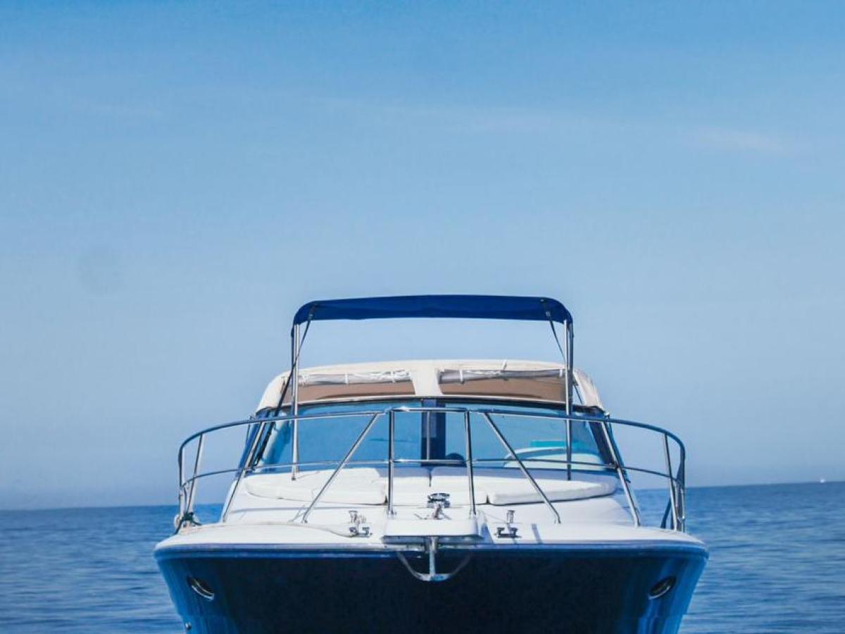 Front view of a boat on calm blue water under a clear sky.
