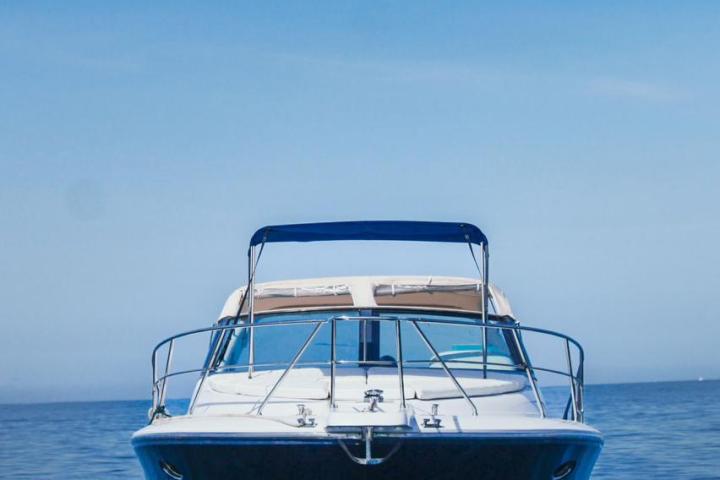 Front view of a boat on calm blue water under a clear sky.
