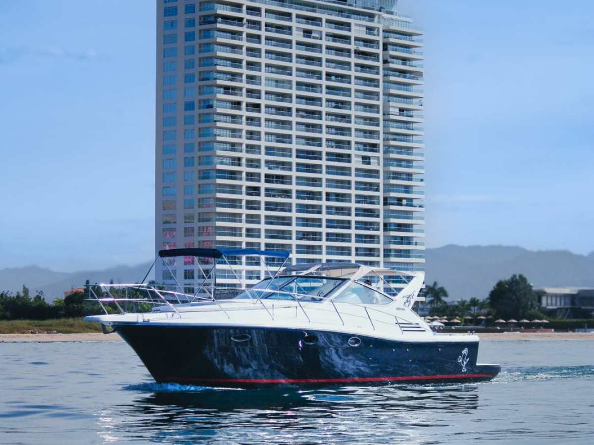 Luxury yacht on water with tall building in background.