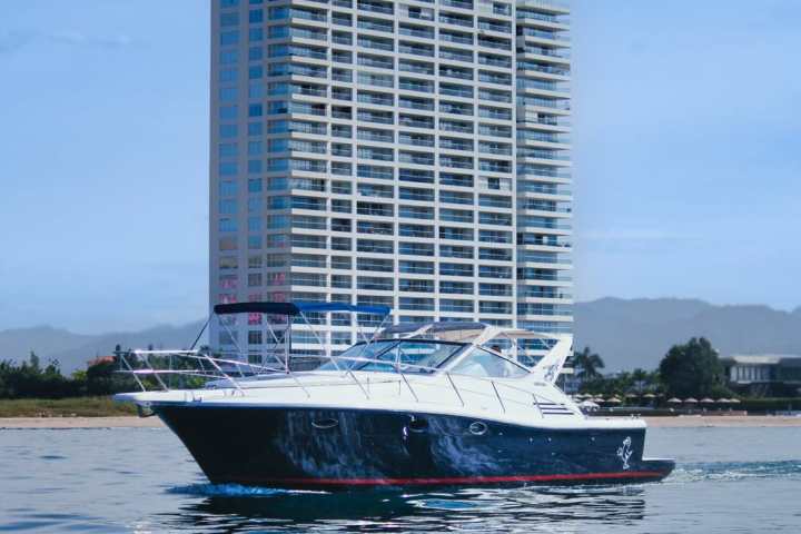 Luxury yacht on water with tall building in background.