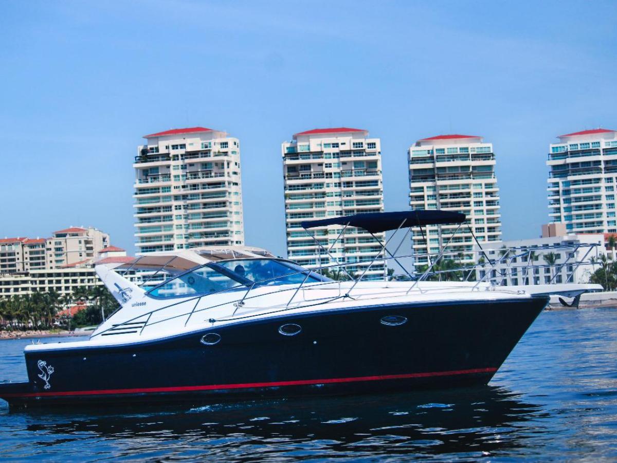 Motor yacht on calm water with city buildings in the background.