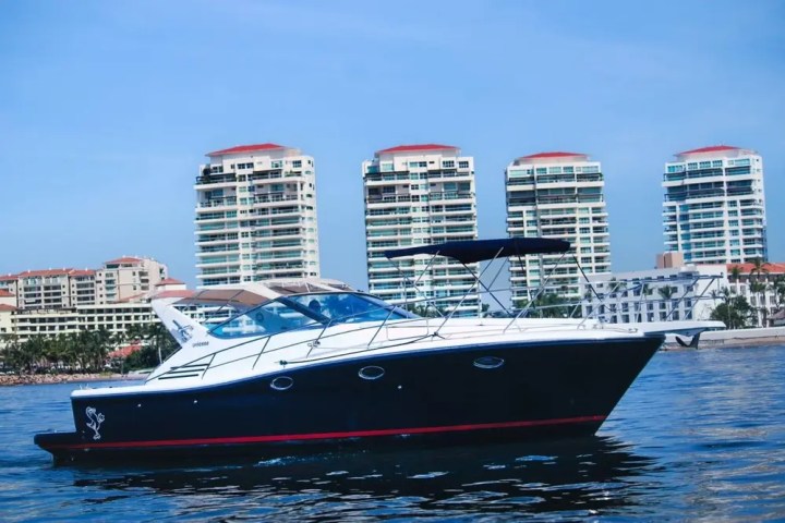 Boat on water with four high-rise buildings in the background.