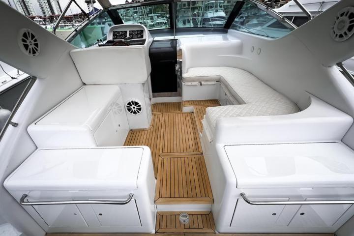 Interior of a yacht with white seats and wooden flooring.