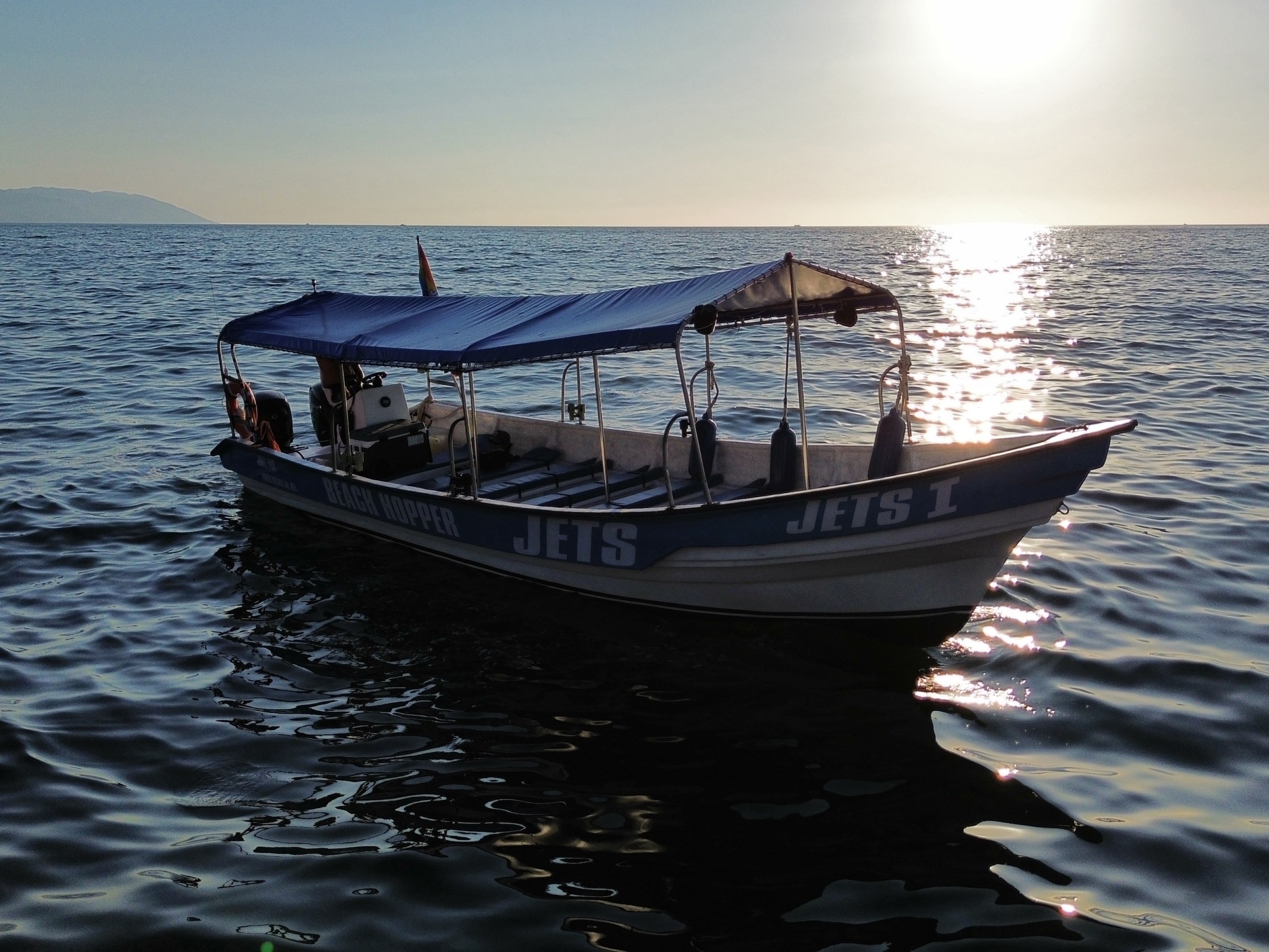 A boat with a canopy on a calm sea during sunset.