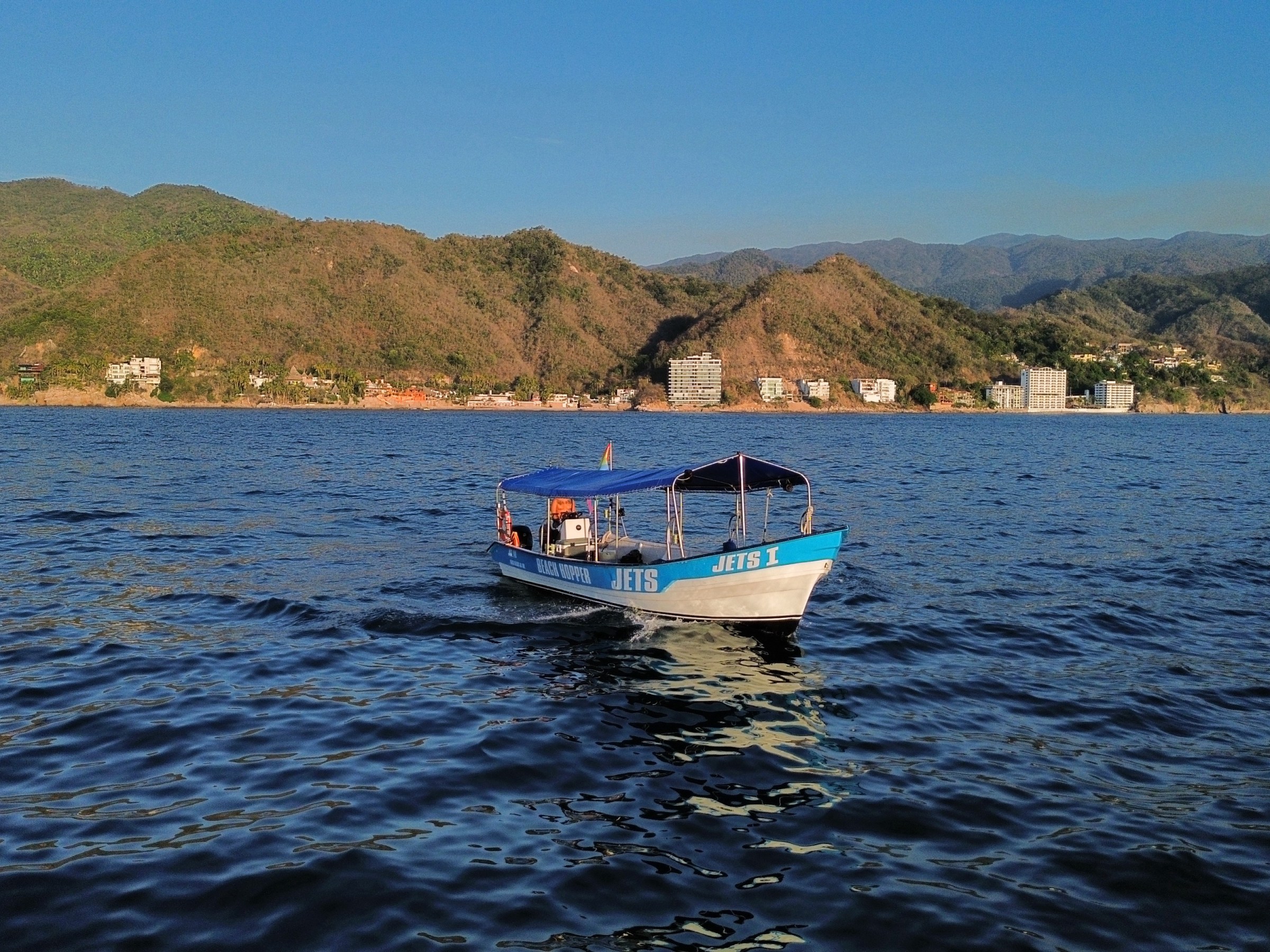 Boat on water with mountains and buildings in the background.