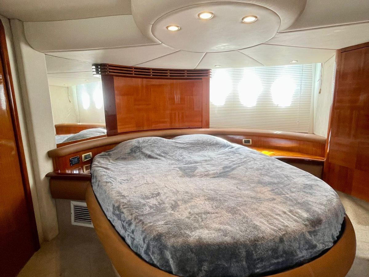 Luxurious yacht bedroom with oval bed and wooden cabinetry.
