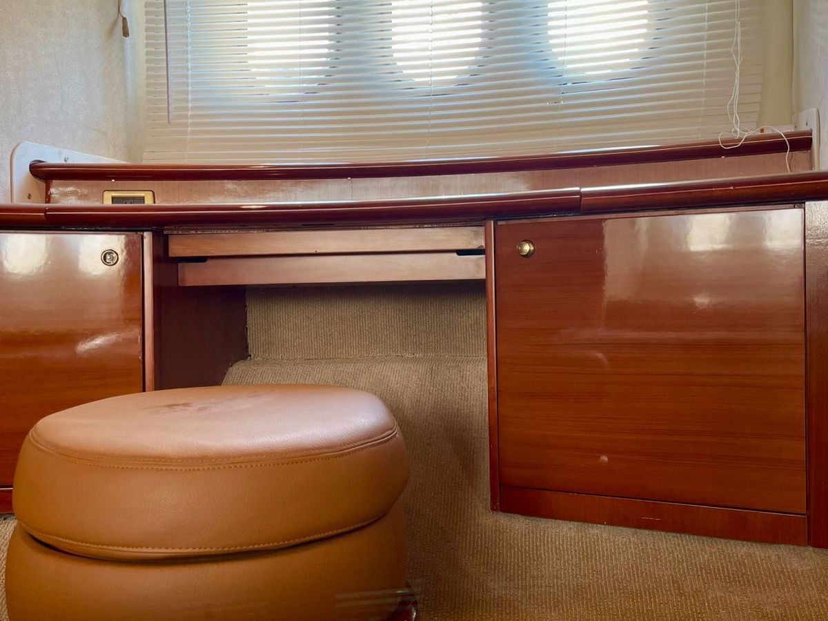 Interior view of a yacht cabin with wooden cabinets and a round ottoman.