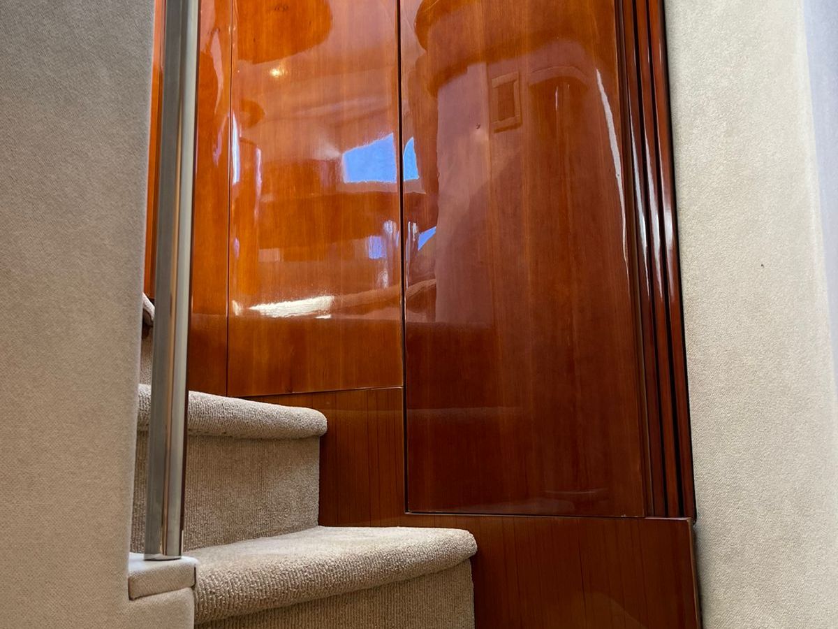 View of luxury yacht interior with carpeted stairs and wooden paneling.