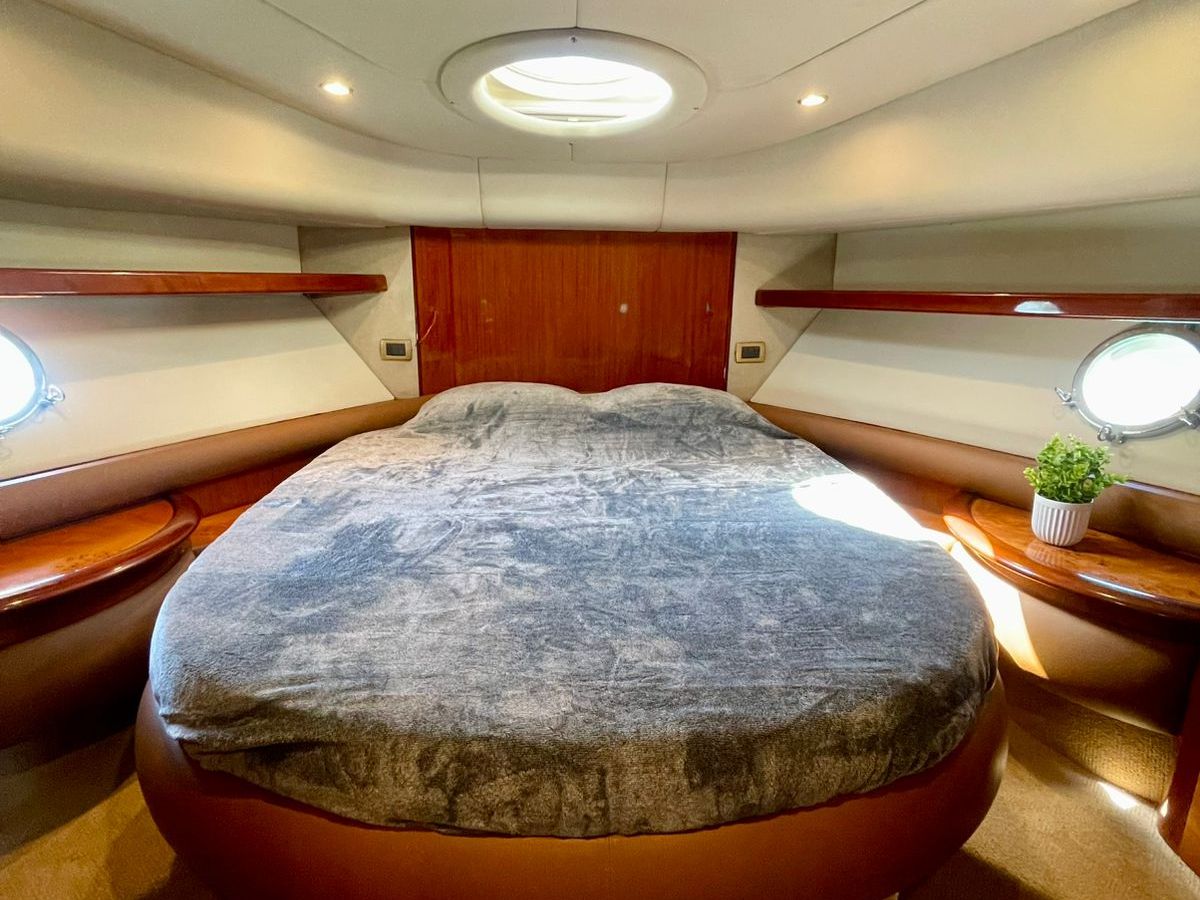 Luxury yacht bedroom with round bed and porthole windows.