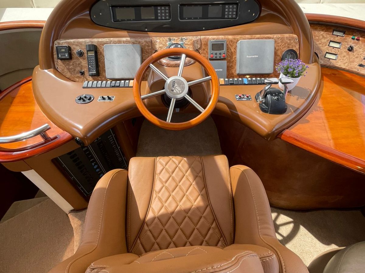 Luxurious yacht helm with brown leather chair and wood-accented control panel.
