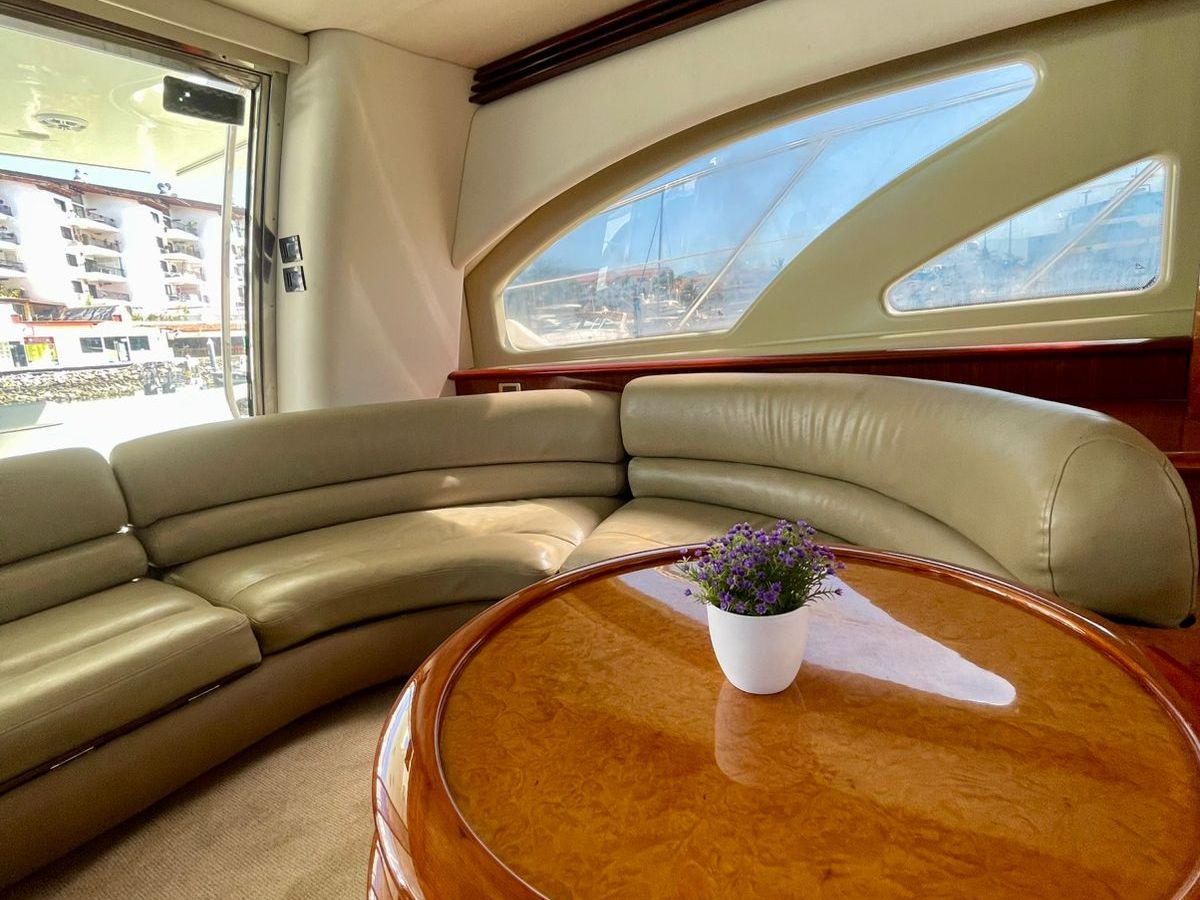 Elegant yacht interior with beige seating, round table, and small potted plant.
