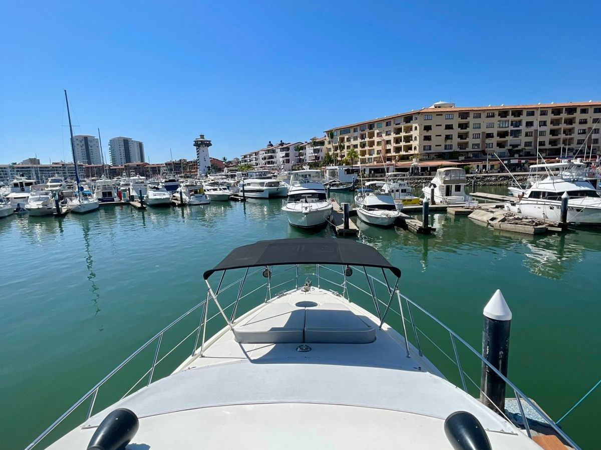 View of marina from a boat, with multiple yachts and a clear blue sky.