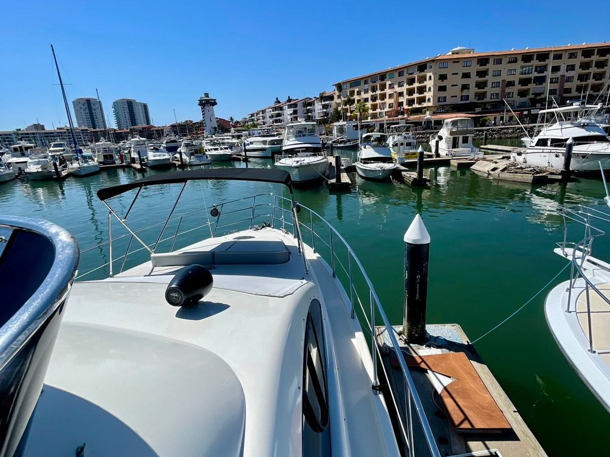 View from a boat deck looking at a marina with multiple boats docked under a clear blue sky.