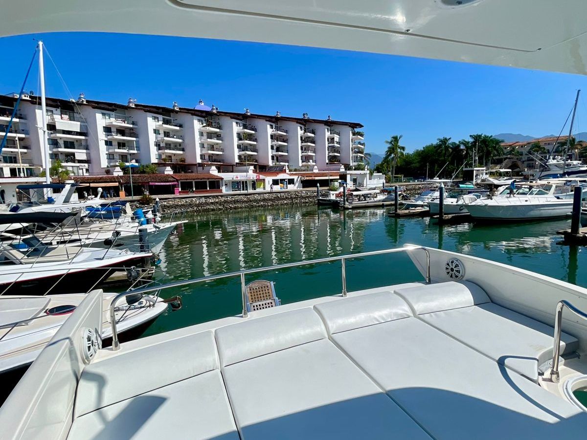 View of a marina from a boat deck, with docked boats and a hotel building in the background.