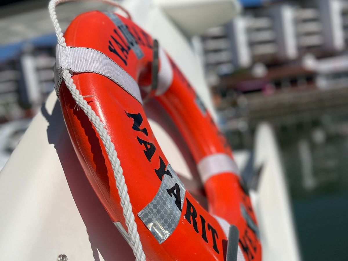Orange lifebuoy on a boat with buildings in the background.