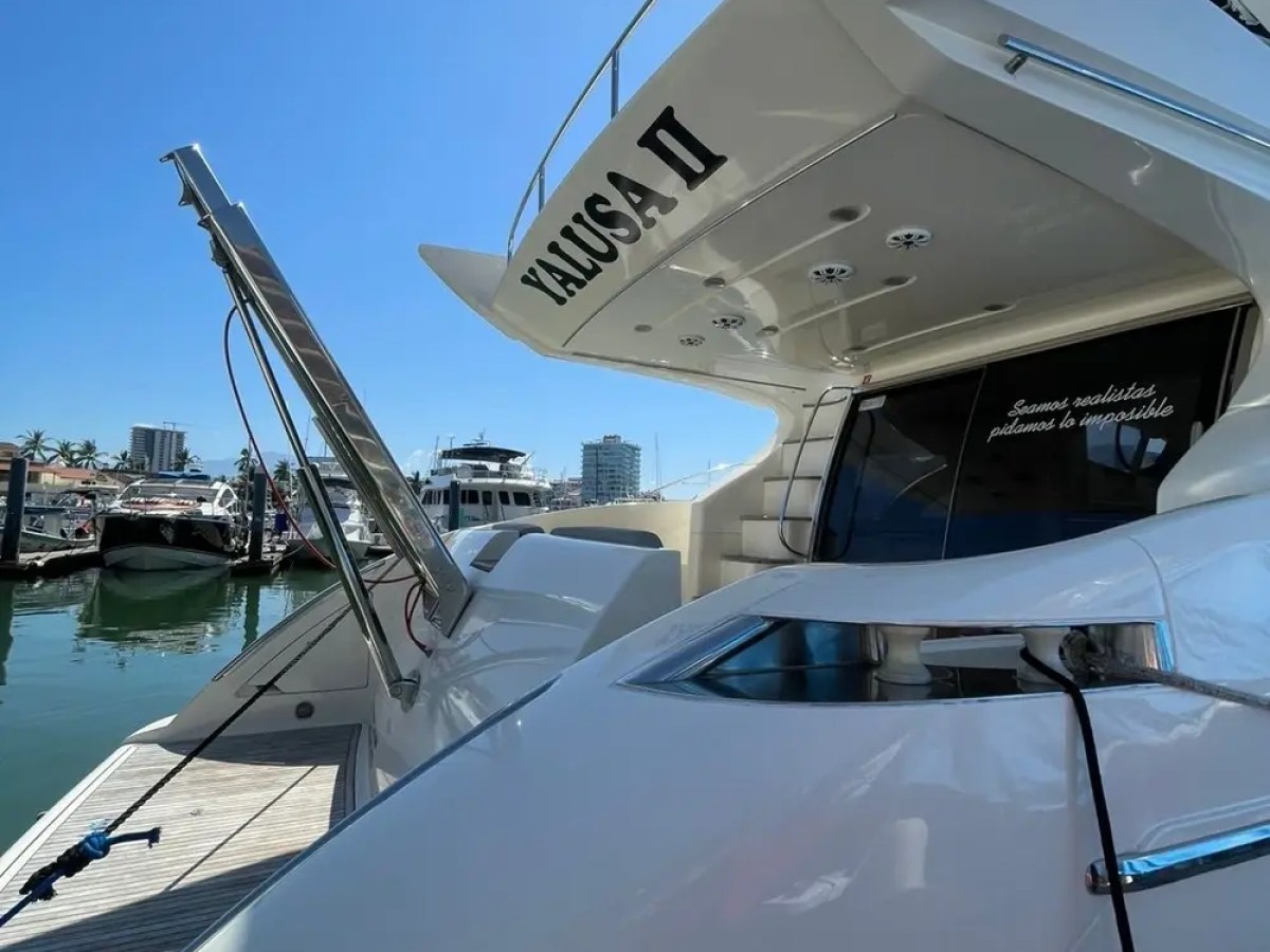 Close-up of a white yacht docked at a marina on a sunny day.
