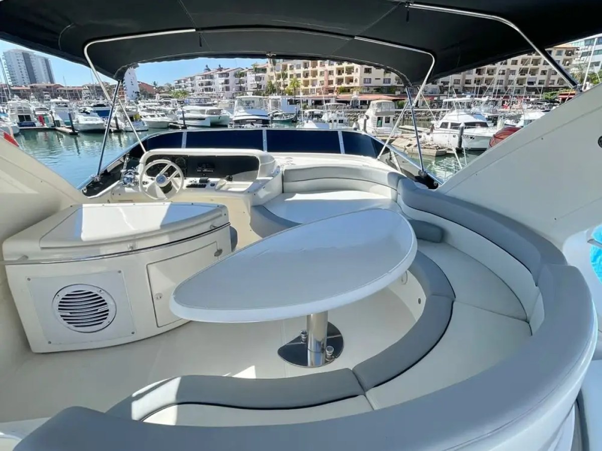 View of yacht seating area with curved bench and table, marina in background.