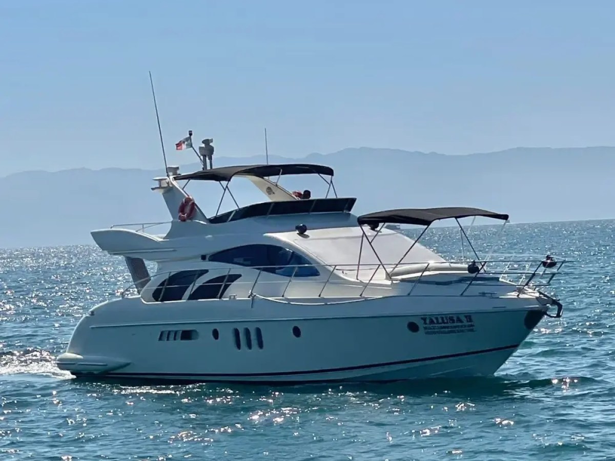 A white yacht sailing on clear blue water under a clear blue sky.