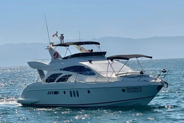 A white yacht sailing on clear blue water under a clear blue sky.