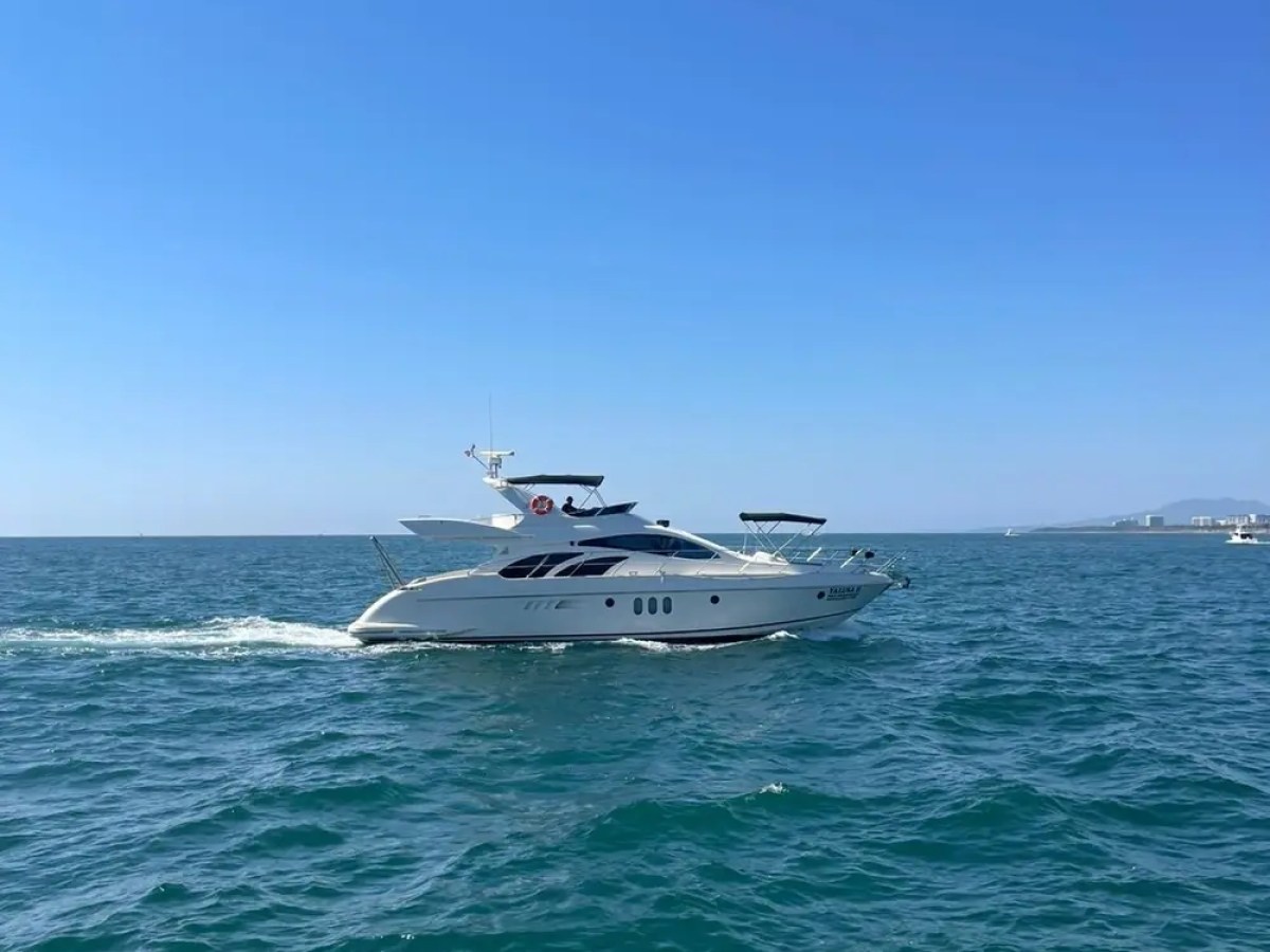 A luxury yacht cruising on a clear blue sea under a bright blue sky.