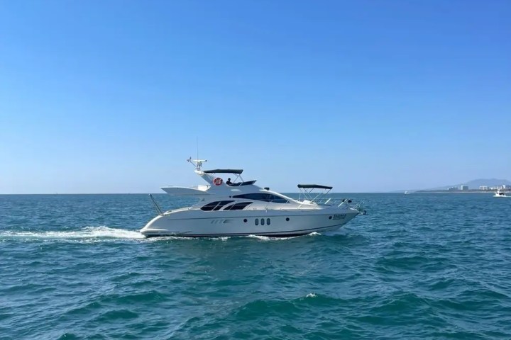 A luxury yacht cruising on a clear blue sea under a bright blue sky.
