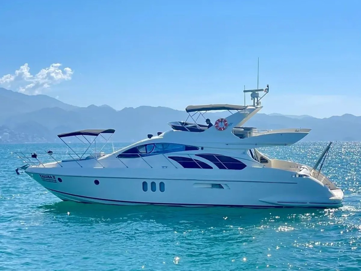White yacht on clear blue water with mountains in the background.