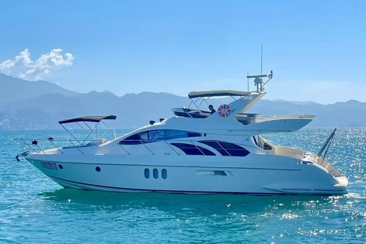 White yacht on clear blue water with mountains in the background.