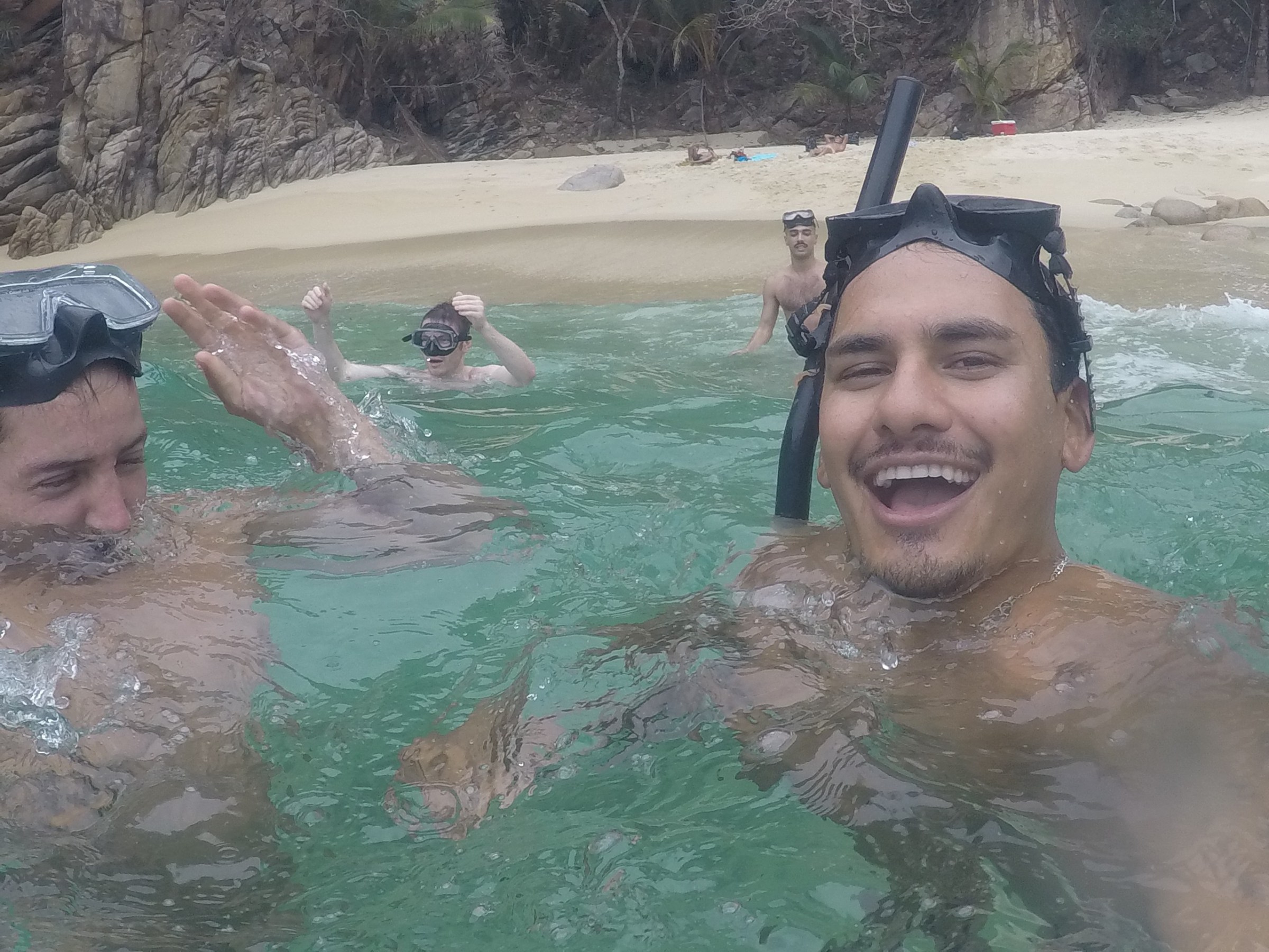 Group snorkeling in clear water near a sandy beach.