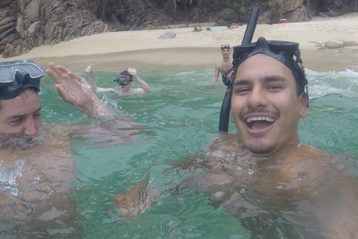 Group snorkeling in clear water near a sandy beach.